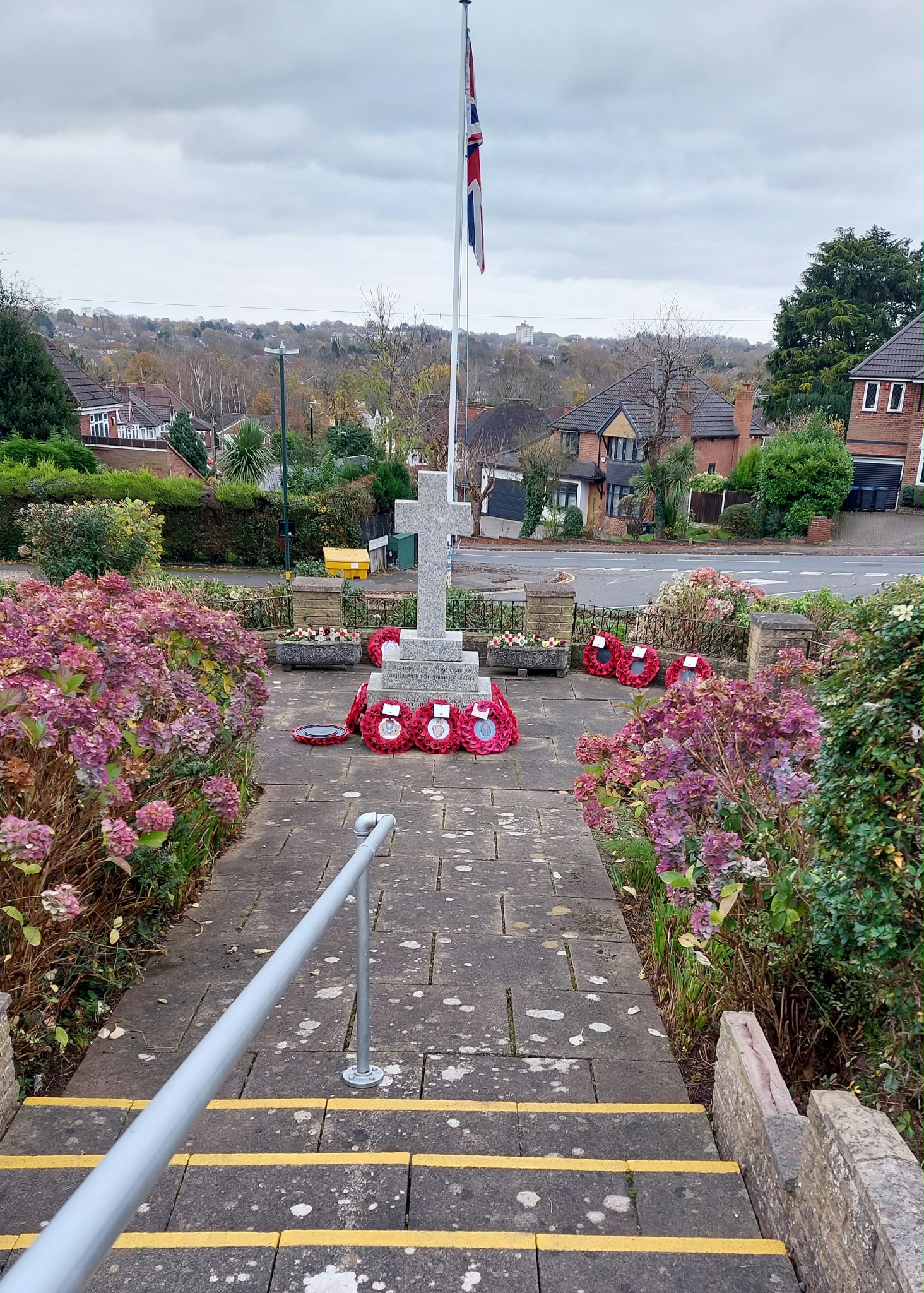 Steps through the Quarry Club gardens leading to a stone memorial with poppy wreaths and a Union flag